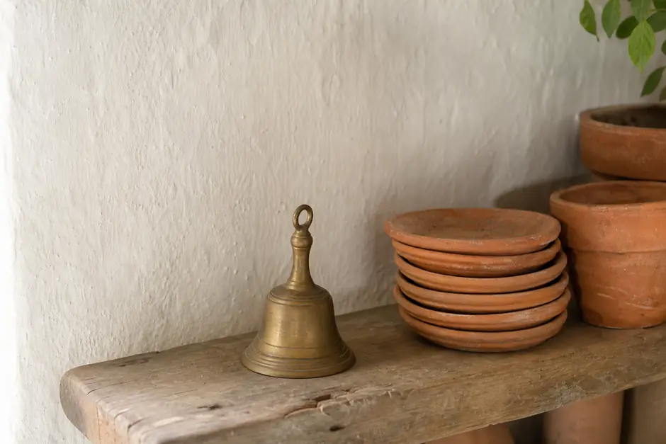 Bacheca di sughero con fogli di carta bianchi appuntati in fila e un campanello di ottone su una mensola (immagine generata con AI)