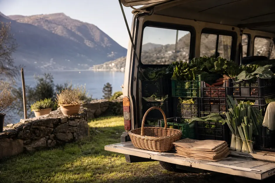 Cesta di vimini e sacchetti di carta sul portellone di un vecchio furgone accanto a un campo (immagine generata con AI)